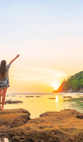Woman celebrating a beach sunset – Fab Holidays, the best travel agency in Delhi.